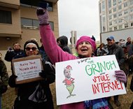 Diane Tepfer holds a sign with an image of Federal Communications Commission (FCC) Chairman Ajit Pai as the “Grinch who Stole the Internet” as she protests near the FCC in Washington today. The FCC voted to eliminate net-neutrality protections for the internet. 