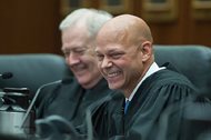 Newly sworn-in Magistrate Judge M. David Weisman reacts as the accolades and jokes come from four speakers at his investiture Thursday at the Dirksen Federal Courthouse. Sitting next to Weisman is Magistrate Judge Michael T. Mason. 